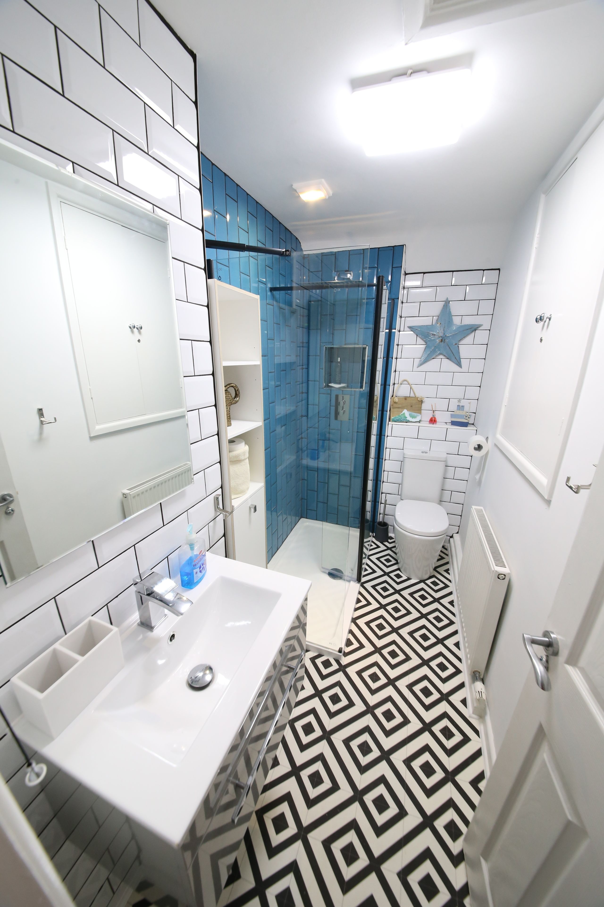 Un baño con lavamanos blanco, cabina de ducha con mampara de vidrio y un inodoro.