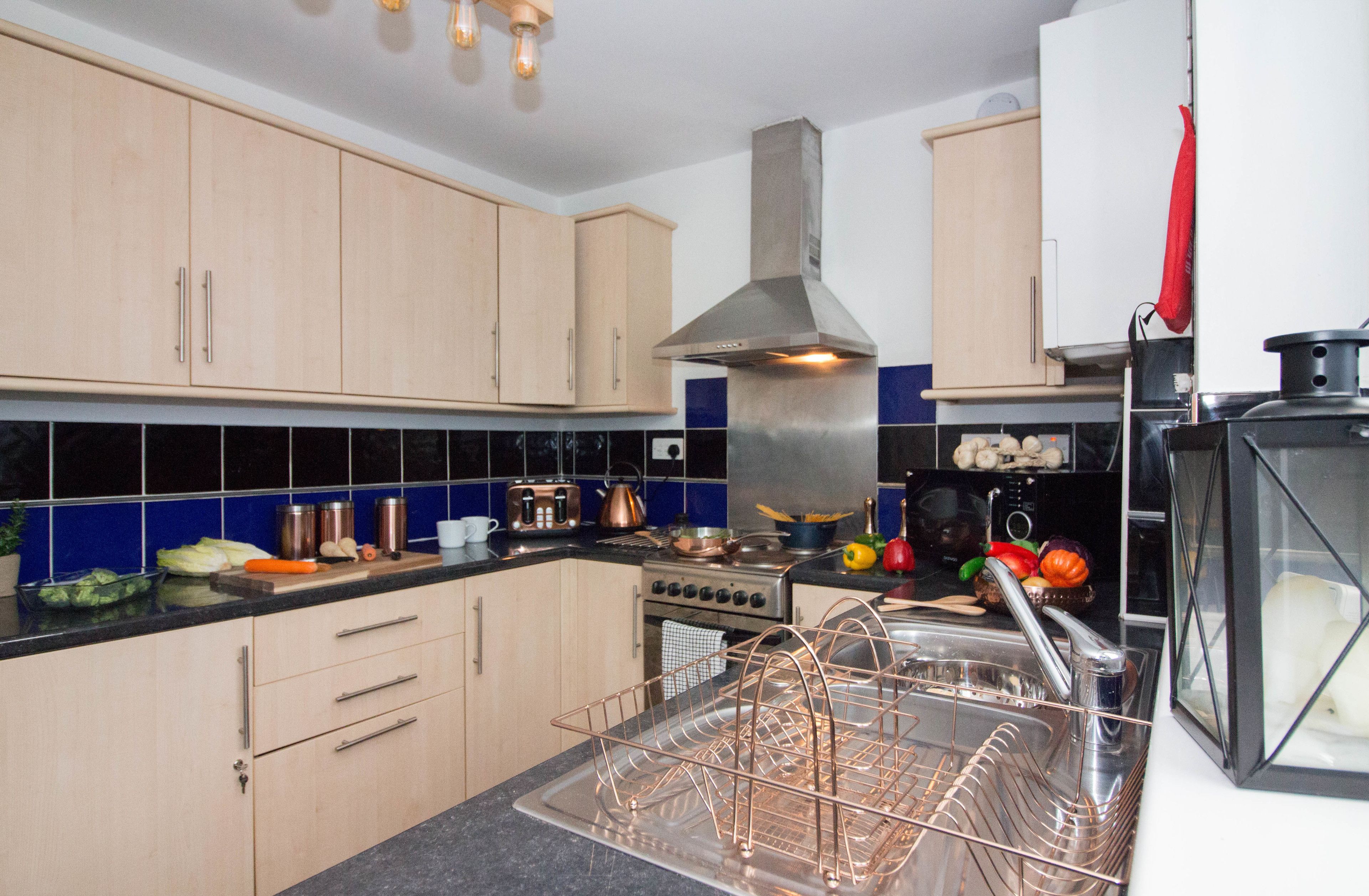 A modern kitchen with wooden cabinets, a stainless steel range hood, and a dishwasher.