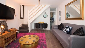 Una sala de estar con un sofá, una mesa de centro, televisor y una escalera.