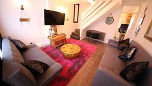 Una sala de estar moderna con un sofá gris, un tapiz rojo y una mesa de centro de madera.