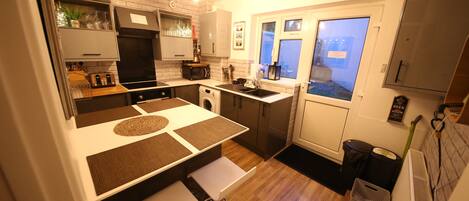 A modern kitchen with white cabinetry, a built-in oven, and a window with a view.