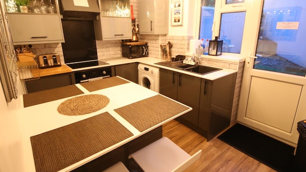 Una cocina moderna con una isla central, electrodomésticos integrados y vistas al exterior por una ventana.