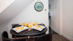Comedor con una mesa dispuesta para dos personas, con platos de comida y vasos de jugo de naranja.