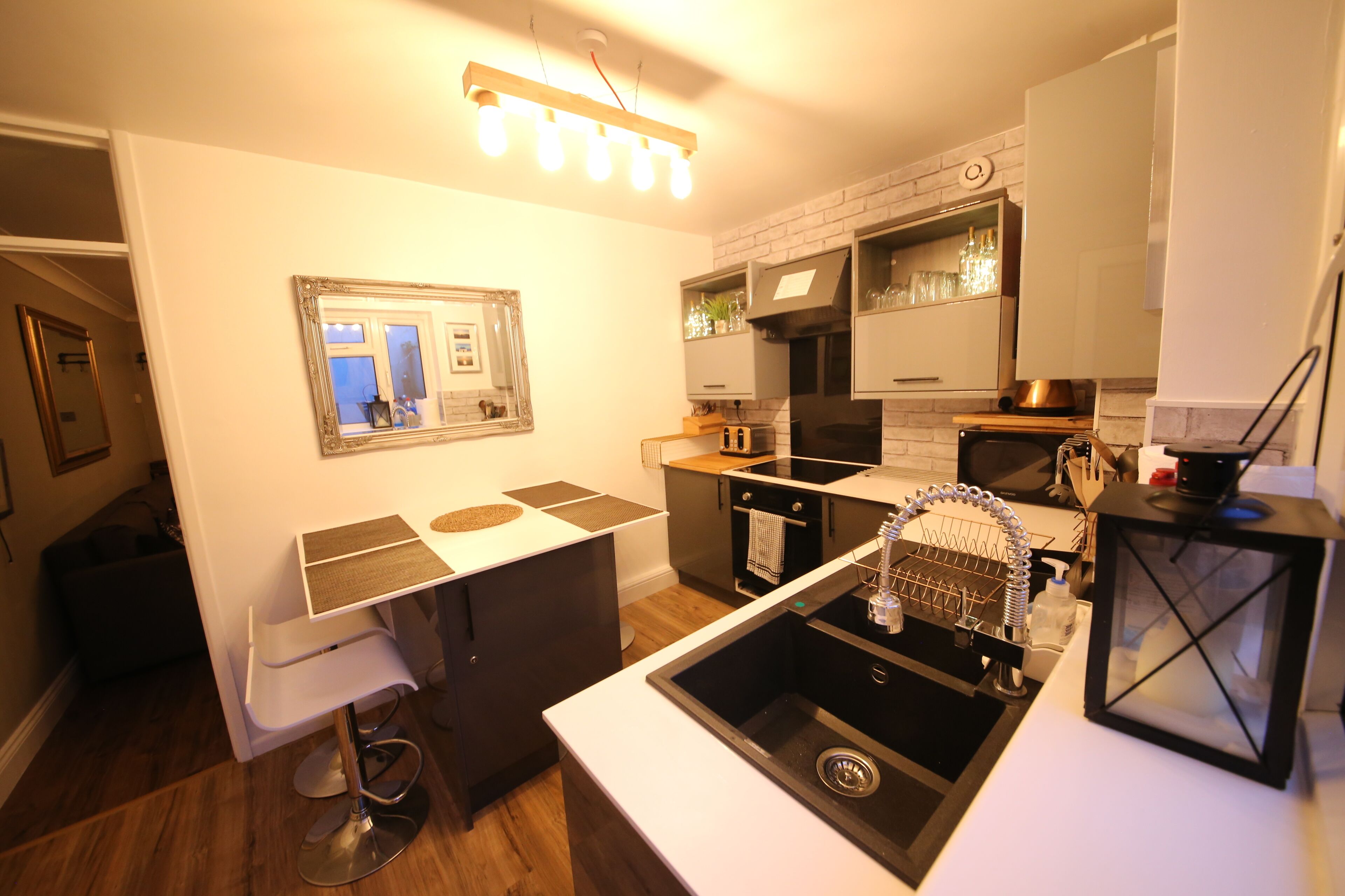 A modern kitchen with white countertops, a black sink, and a hanging light fixture.