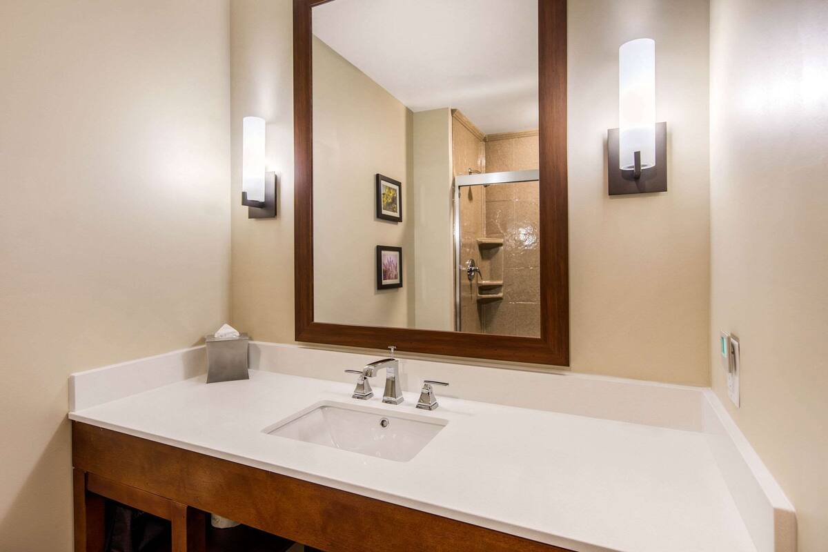 A bathroom with a white sink, a large mirror, and two wall-mounted light fixtures.