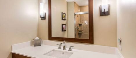 Un baño con un lavabo blanco, un espejo grande y dos luces fijadas a la pared.