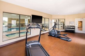A gym with treadmills, an elliptical, and a rowing machine. There is a pool visible through the glass doors. - Comfort Suites Liberal North (Liberal)