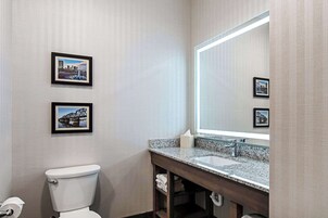 Un baño con inodoro, lavamanos y dos cuadros en la pared.