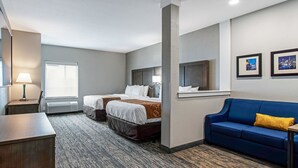 Una habitación de hotel con dos camas, un sofá azul, un escritorio y una ventana con persianas.