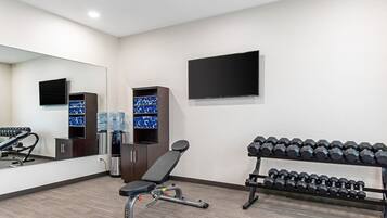 Un gimnasio con equipo de ejercicio, dispensadores de agua y una televisión en la pared.