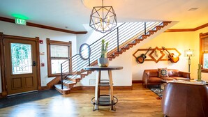 A spacious living area with a wooden staircase, a round table with a plant, and a leather sofa. - The Curtis Park Club (Denver)