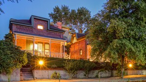 A large, two-story house with a brick facade, a balcony, and a well-maintained garden. - The Curtis Park Club (Denver)