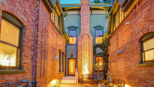 A brick building with a central chimney, a bench, and a small garden area. - The Curtis Park Club (Denver)