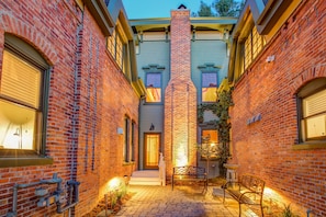 A brick building with a central chimney, a bench, and a small garden area. - The Curtis Park Club (Denver)