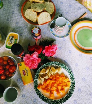 A table with various food items, including bread, fruits, and a bowl of sliced vegetables. - Quarumanu Area (Tanna Island)