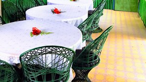 Un restaurante con paredes verdes, mesas blancas y sillas verdes.