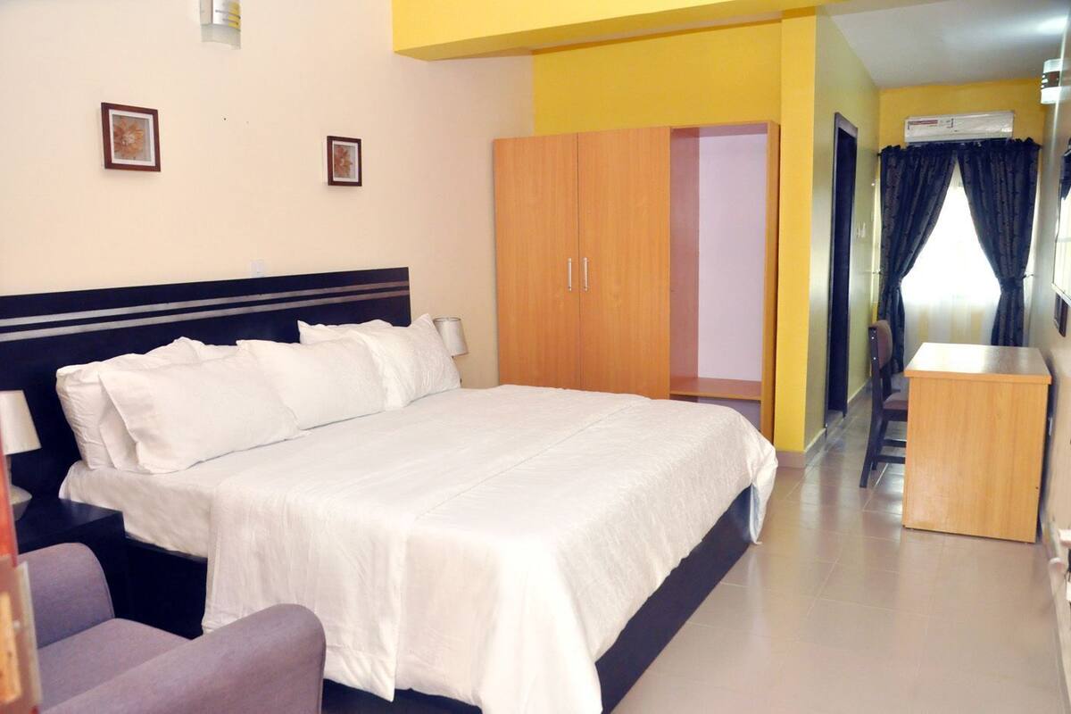 A hotel room with a bed, a wardrobe, a desk, and a chair.