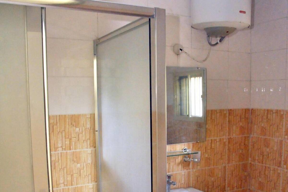 A bathroom with a shower, a sink, a mirror, and a water heater.