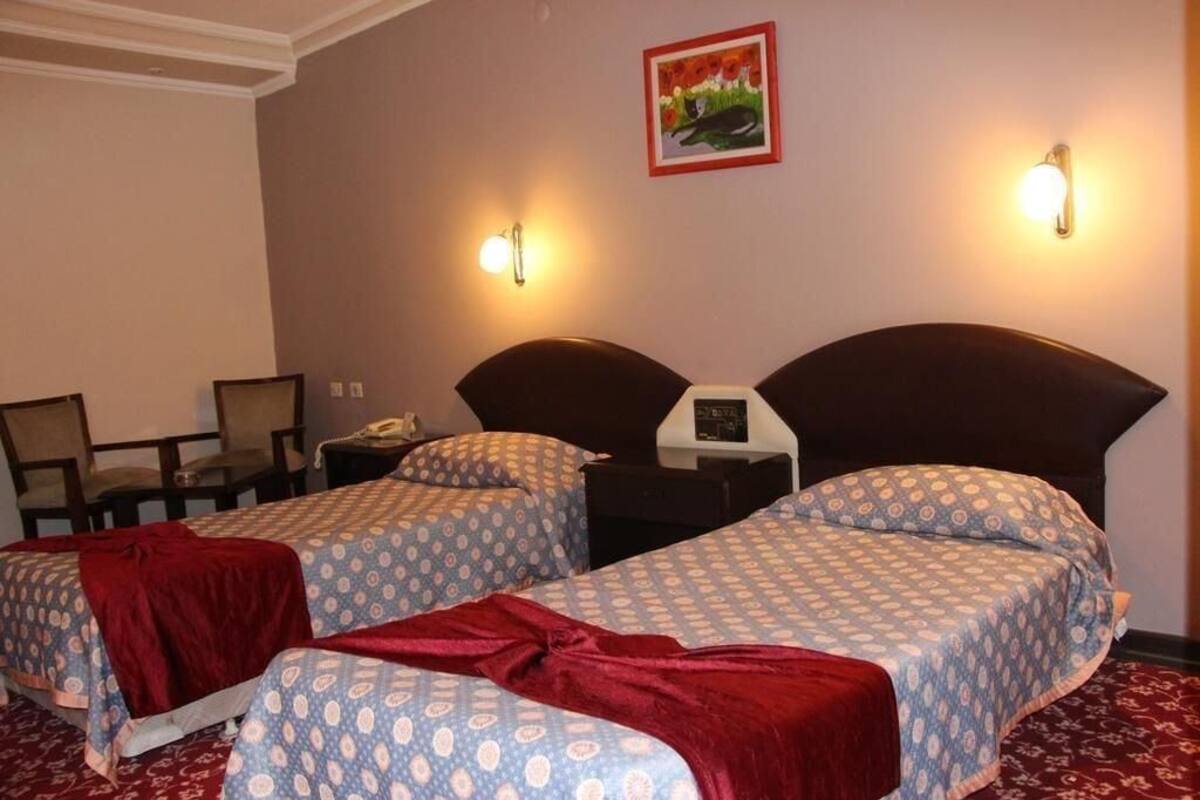 A hotel room with two beds, a desk, a chair, and a nightstand with a phone.