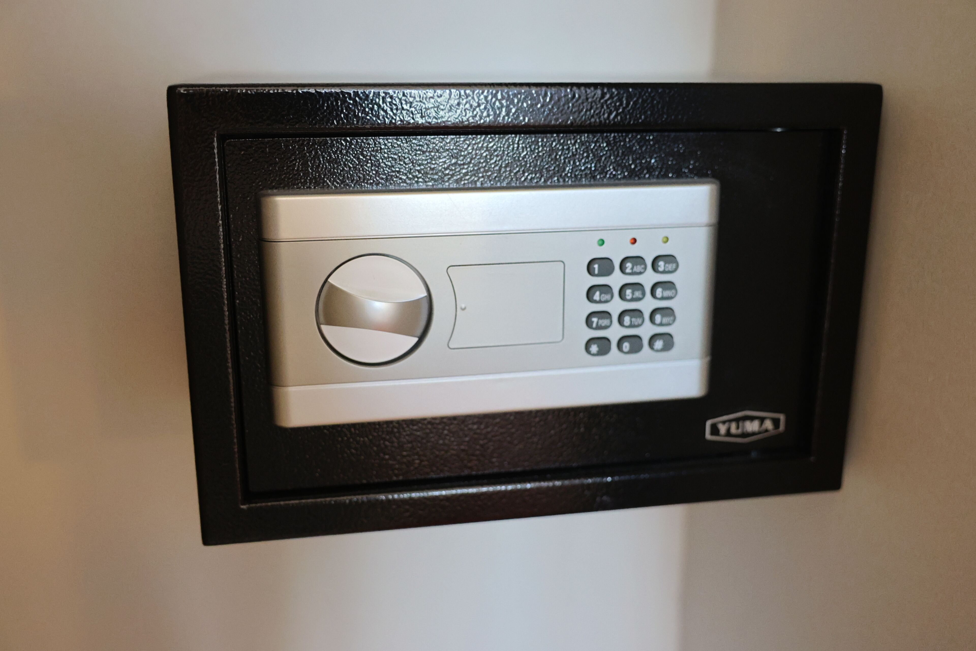 A security keypad with a numeric keypad and a round button, labeled 'YUMA'.