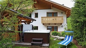 A wooden deck with a hot tub, a lounge chair, and a wooden pergola. - Bergerhof (Sarentino)