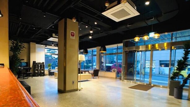 A spacious lobby with a reception desk, seating area, and large windows offering a view of the street. - Renaissance Hotel - Hostel (Jeju City)