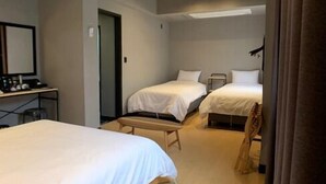 A hotel room with two beds, a desk with a chair, and a mirror on the wall. - Renaissance Hotel - Hostel (Jeju City)
