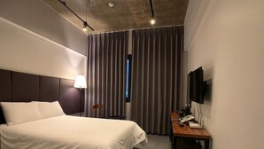 A modern hotel room with a large bed, a desk with a lamp, and a TV on the wall. - Renaissance Hotel - Hostel (Jeju City)