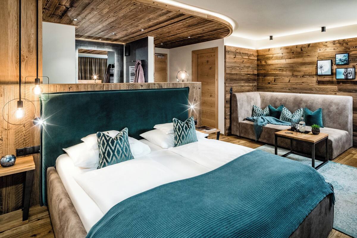 Ein modernes Schlafzimmer mit einem großen Bett, einer Couch und einer Wand mit Holzelementen.