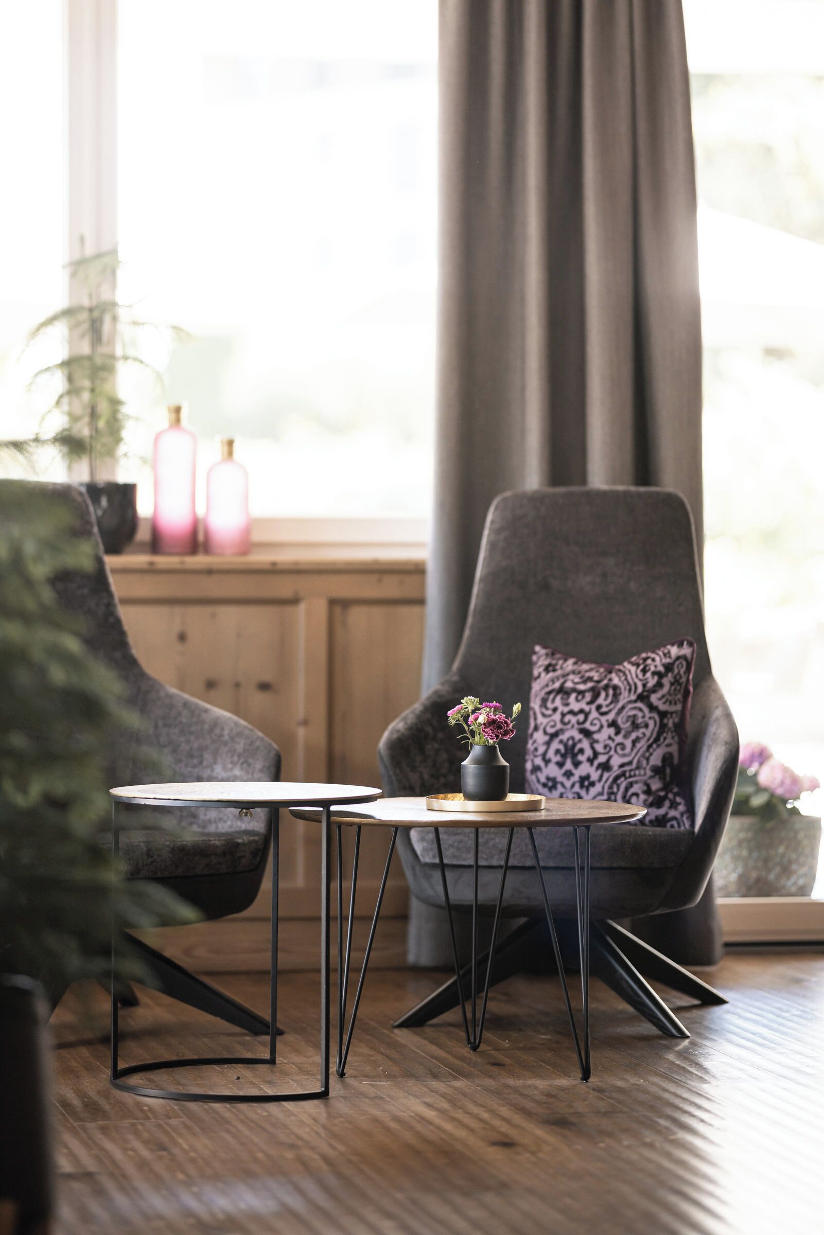 Una sala moderna con un sillón gris oscuro, una mesita redonda y una planta en maceta.