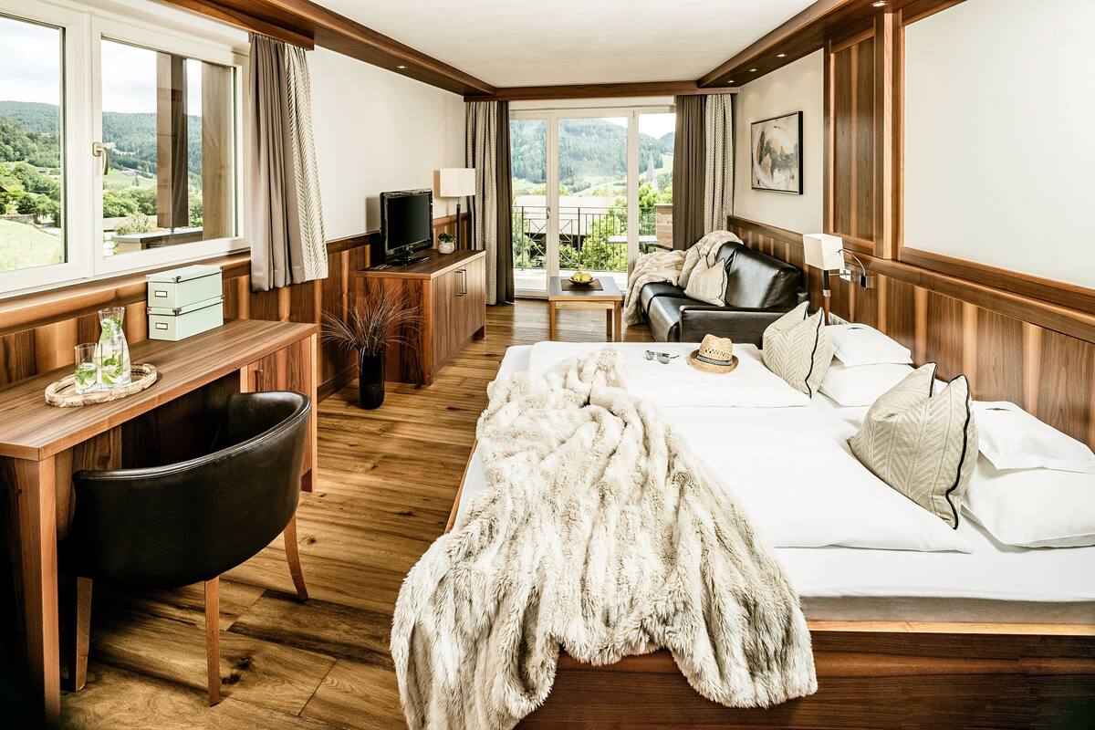 Ein Hotelzimmer mit Bett, Schreibtisch, Fernseher und Blick ins Freie.