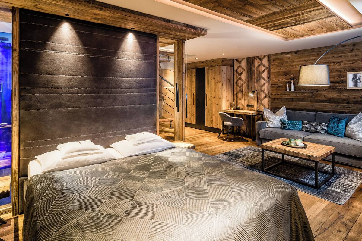 Ein modernes Schlafzimmer mit einem großen Bett, einem Holzkopfende, einem Schreibtisch und einem Sofa.