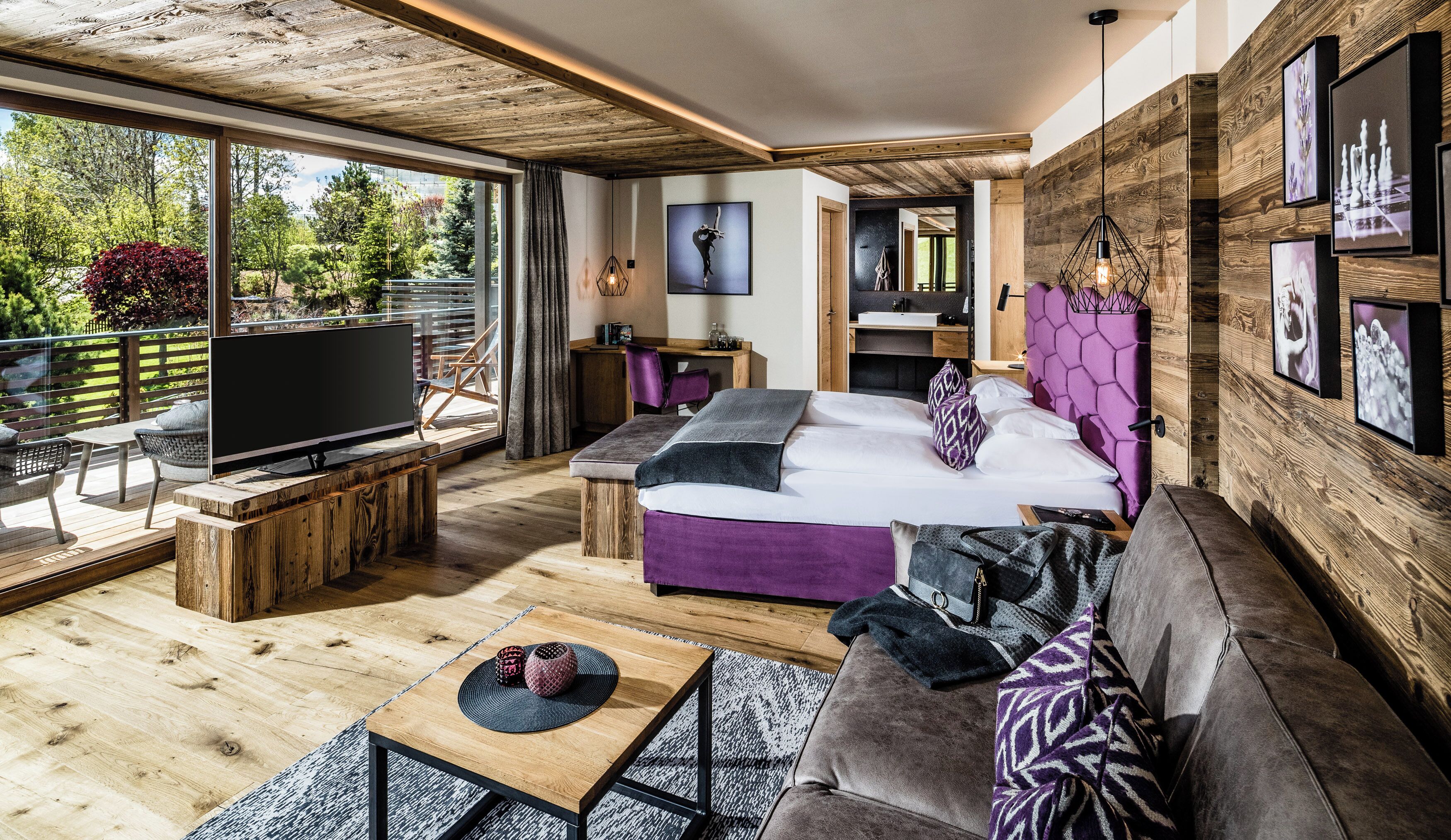Ein modernes Schlafzimmer mit einem großen Bett, einem Fernseher und einem Balkon mit Gartenmöbeln.