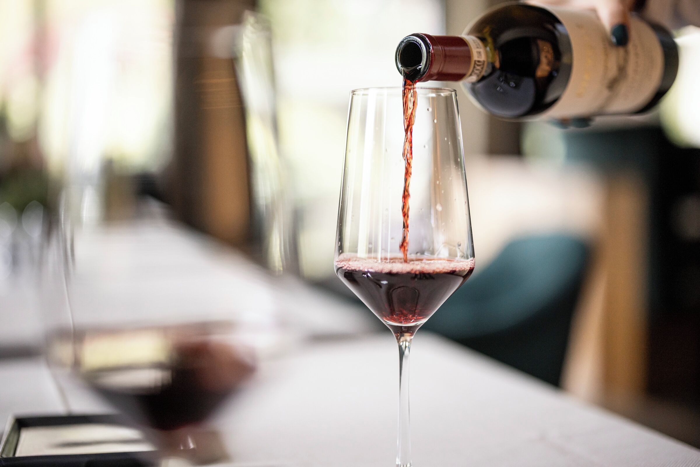 Una botella de vino vertiendo vino en una copa.