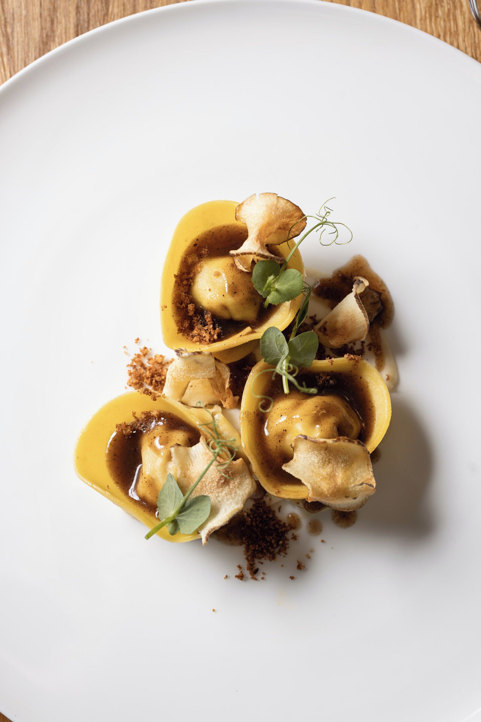 Un plato de ravioles con salsa marrón y hierbas como guarnición.