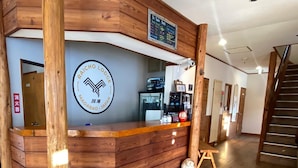 A reception desk with a wooden finish, a logo, and a chalkboard menu. - Raicho Lodge Madarao (Iiyama)