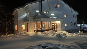 A large, two-story house with multiple windows and a covered porch, surrounded by snow. - Raicho Lodge Madarao (Iiyama)