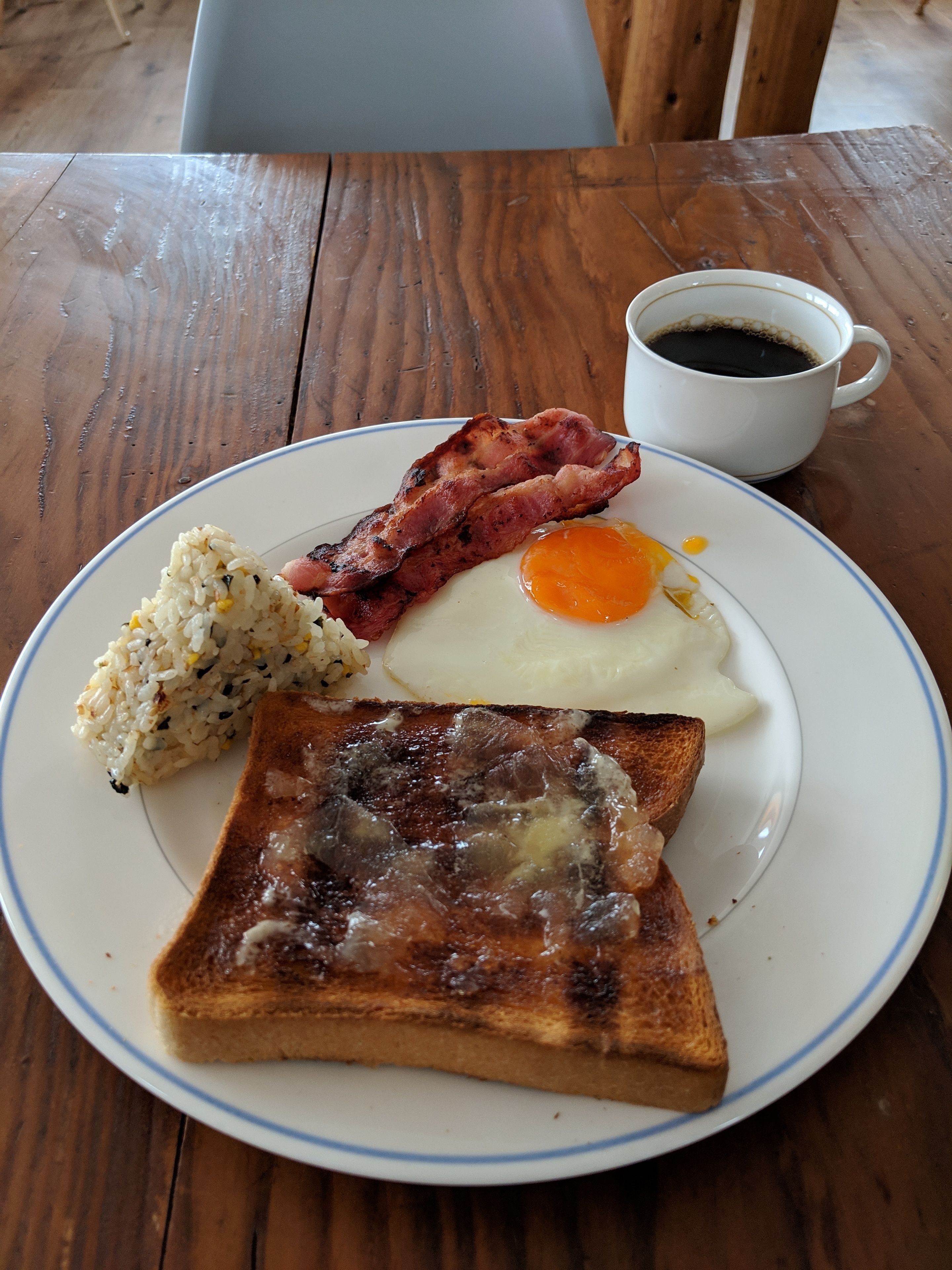 En tallerken med ristet brød, stegt æg, bacon og ris.