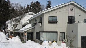 A two-story building with a flat roof and a snow-covered ground. - Stayful House Nakamachi (Hakuba)