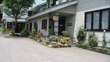 A building with a covered entrance, potted plants, and a sign indicating a business.