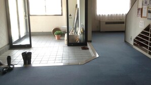 A room with a tiled floor, a potted plant, a mirror, and a staircase. - Stayful House Nakamachi (Hakuba)
