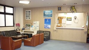 A reception area with a desk, chairs, and a bulletin board. - Stayful House Nakamachi (Hakuba)
