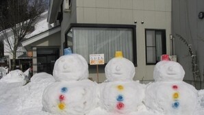 Three snowmen with colored buttons in front of a building. - Stayful House Nakamachi (Hakuba)