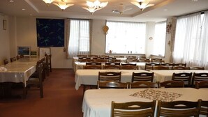 A large dining hall with multiple tables and chairs, arranged in rows. - Stayful House Nakamachi (Hakuba)