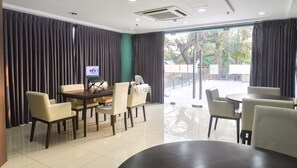A modern hotel room with a dining area, a laptop on the table, and a view of the outdoors. - Home Solutions in Padgett Place (Cebu City)