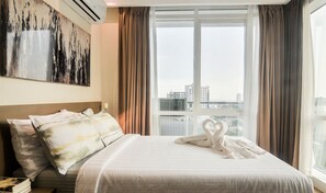 A hotel room with a large bed, a painting on the wall, and a view of the city through the window. - Home Solutions in Padgett Place (Cebu City)