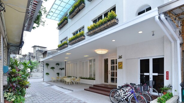 A hotel entrance with a covered patio, potted plants, and bicycles parked outside. - Ing Wang Hotel (Tainan)