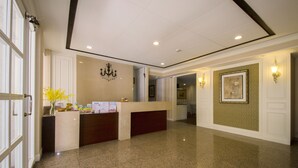 A reception area with a marble counter, a chandelier, and framed artwork on the walls. - Ing Wang Hotel (Tainan)