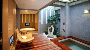 Un moderno espacio de spa con una terraza de madera, una camilla de masaje y una pequeña piscina.