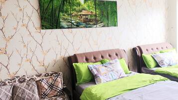 A bedroom with two beds, a sofa, and a wall-mounted painting of a bamboo forest.